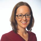 Woman in a red jumper with brown shoulder-length hair and glasses, smiling at the camera