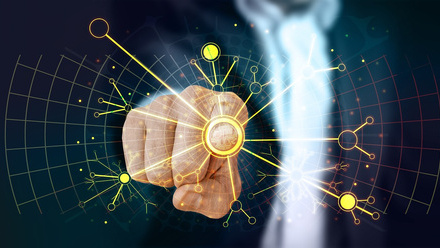 A person in a suit is pointing forward, with their finger touching a glowing circular interface. 