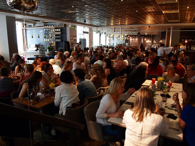A room full of people who are sitting at tables enjoying a meal