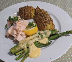 A plate with salmon, potatoes, asparagus, lemon and hollandaise sauce on it