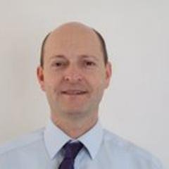 Middle-aged man wearing blue shirt and tie, smiling 
