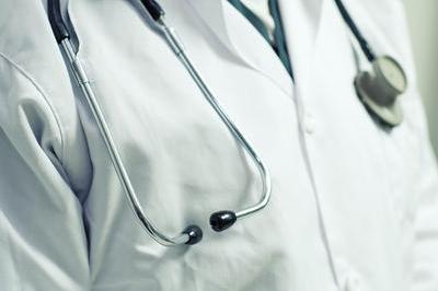 Close-up of a medical stethoscope with black earpieces and silver tubing draped around the neck of a healthcare professional wearing a white coat