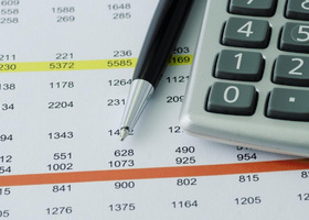 A financial budget spreadsheet, with the bottom left corner of a calculator and a pen on top of it 