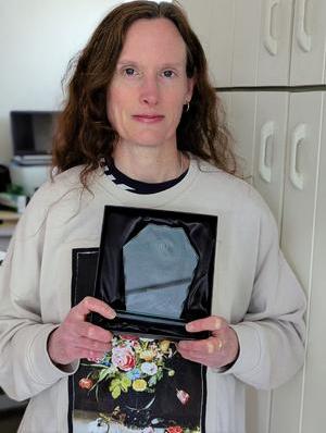 Woman in white jumper holding an award