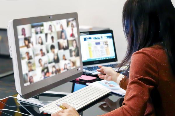 Over the shoulder photo of a woman working on a desktop computer. The screen is filled with pictures of people 