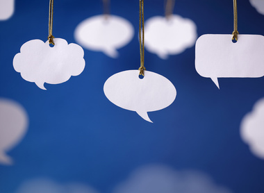 Image of three different styles of speech bubble hanging from the top of the picture frame. In the background are more speech bubbles on a blue back