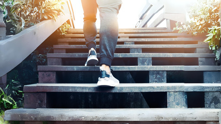 Woman in trainers climbing steps into sunshine