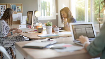 Three people sat at a table all working 