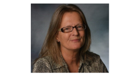 Lady with blond shoulder-length hair and glasses, looking at the camera. She is wearing an animal print shirt 