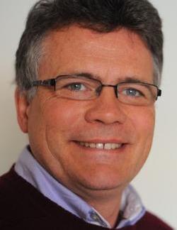 Middle-aged man with grey hair and glasses, smiling
